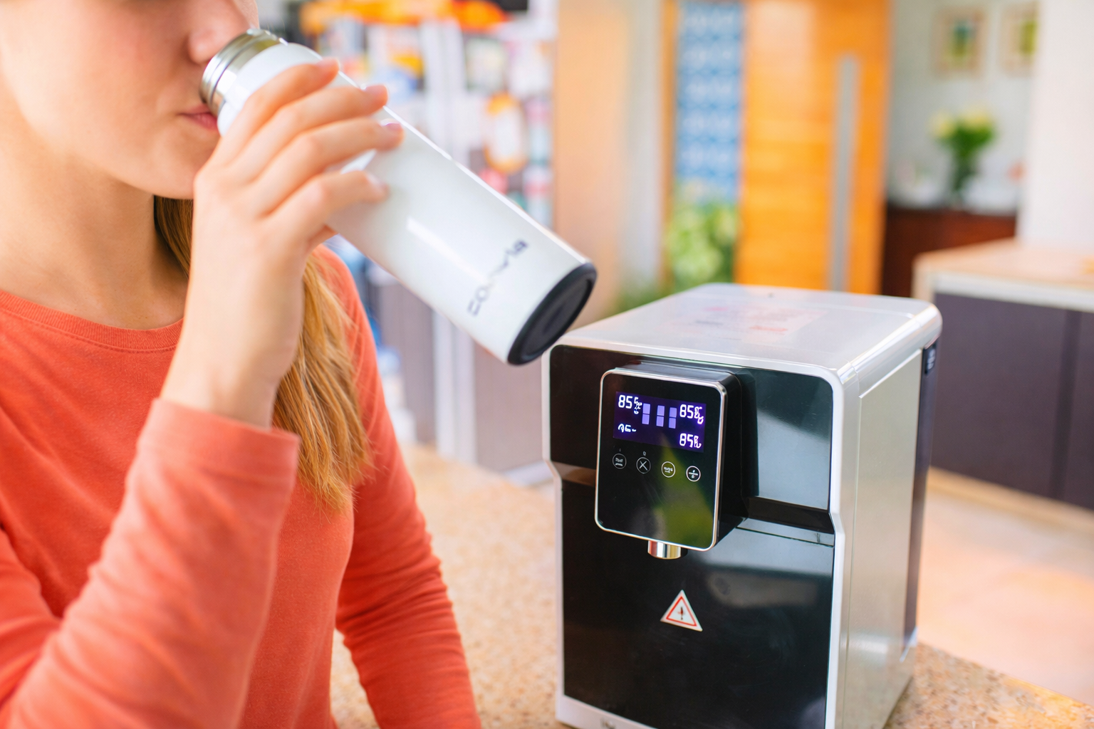 Persona tomando agua purificada en casa con un purificador de agua.